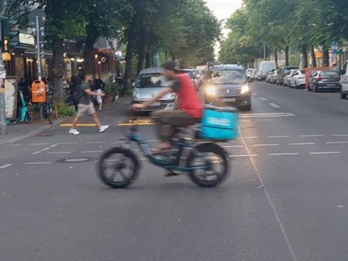 Vorbeifahrender Rider eines Essenslieferdienstes in Berlin.