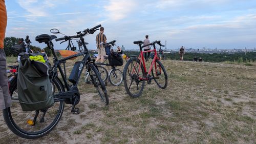 Verschiedene Fahrräder stehen auf dem Drachenberg. Im Hintergrund ist die Skyline Berlins sichtbar.